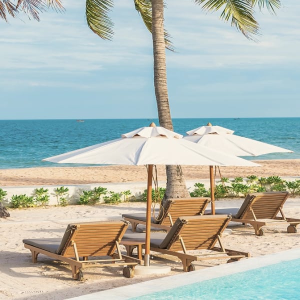 Transats et parasols sur le sable, près de la piscine du beach club